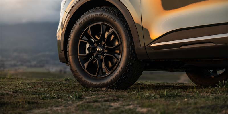 A close-up view of Kia vehicle’s black alloy wheel and tire parked