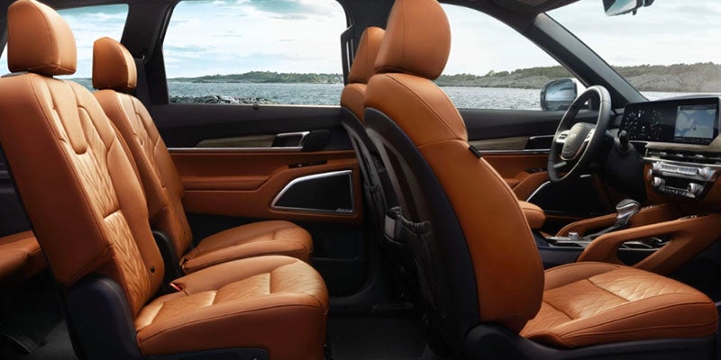 The interior of an Kia featuring two rows of tan leather seats