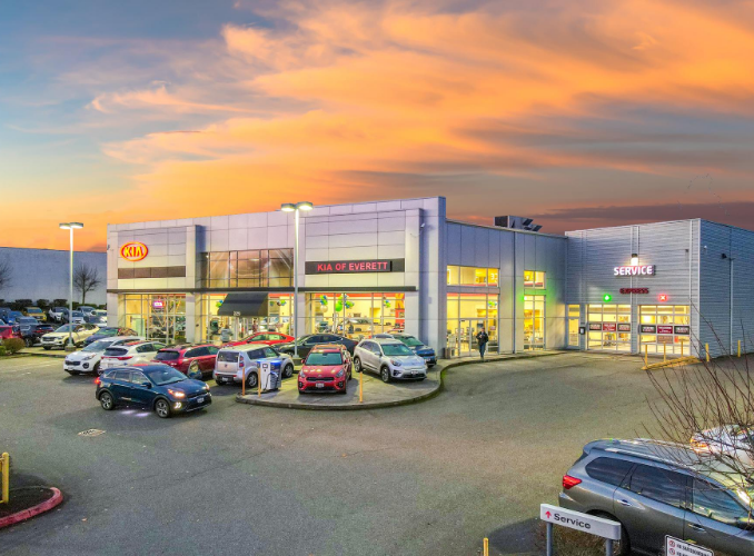 A car dealership building at sunset, with multiple parked vehicles