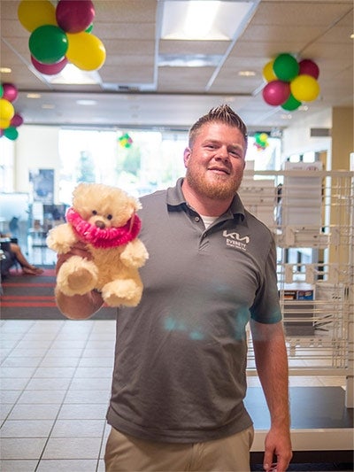 A person wearing a collared shirt with a logo is standing indoors