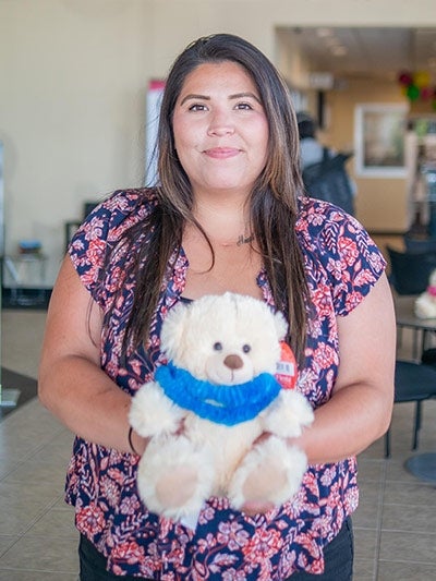 person stands indoors holding a white teddy bear