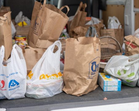 Interior of a vehicle filled with various paper and plastic grocery donation bags.