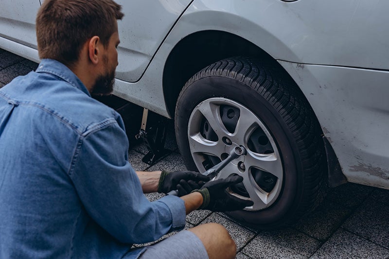 A Person using a power tool to tighten the lug nuts on a vehicle wheel