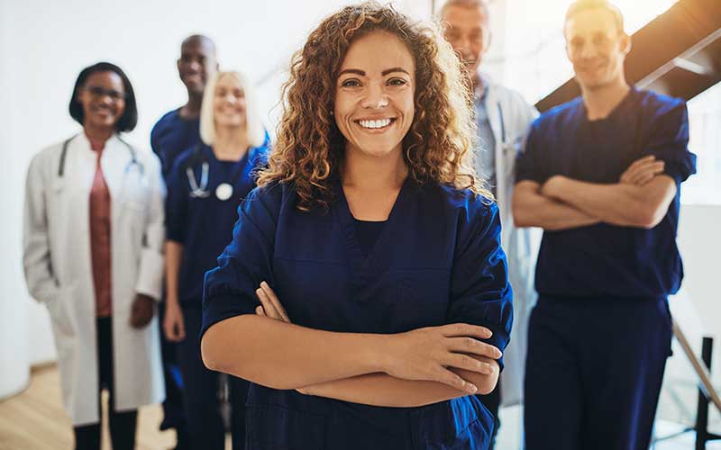 A diverse group of smiling medical professionals standing together in a hallway
