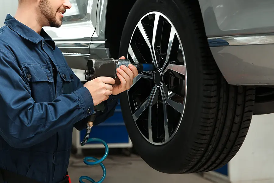 A technician using a power tool to tighten the lug nuts on a vehicle wheel