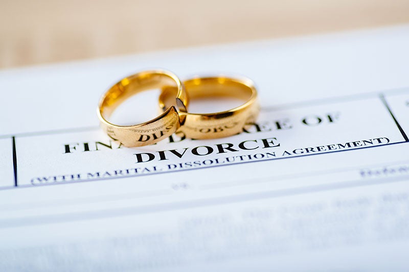 Two gold wedding rings resting on a formal divorce decree document.